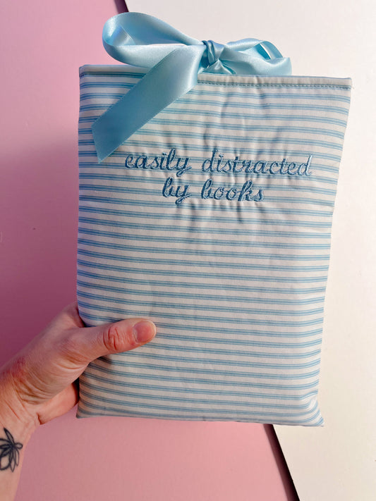 easily distracted by books (light blue text) - embroidered paperback sleeve