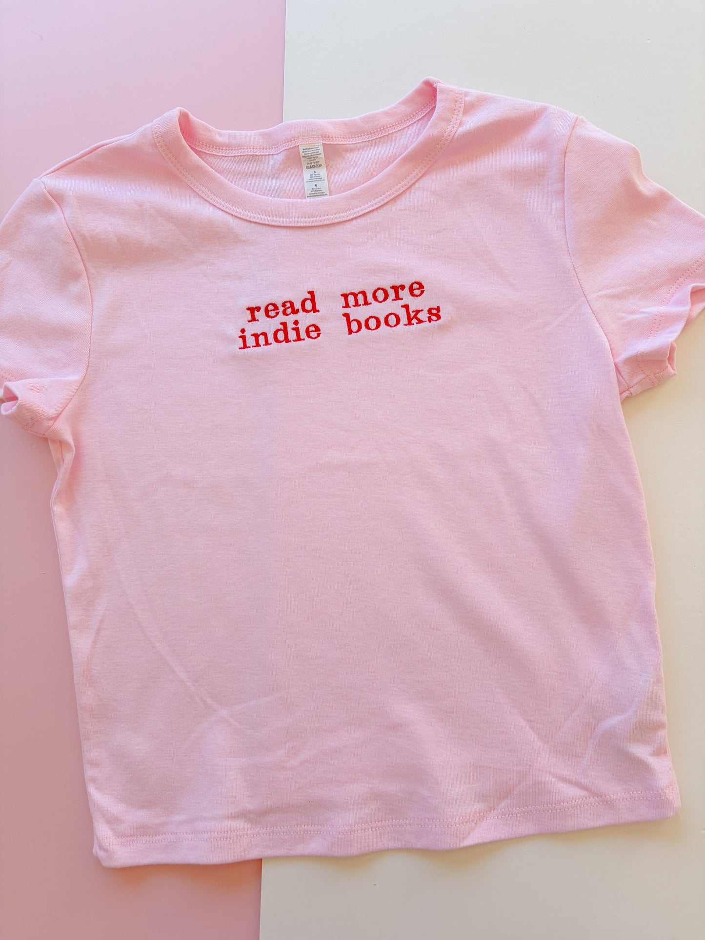 read more indie books embroidered baby tee - Meg the book goblin collab