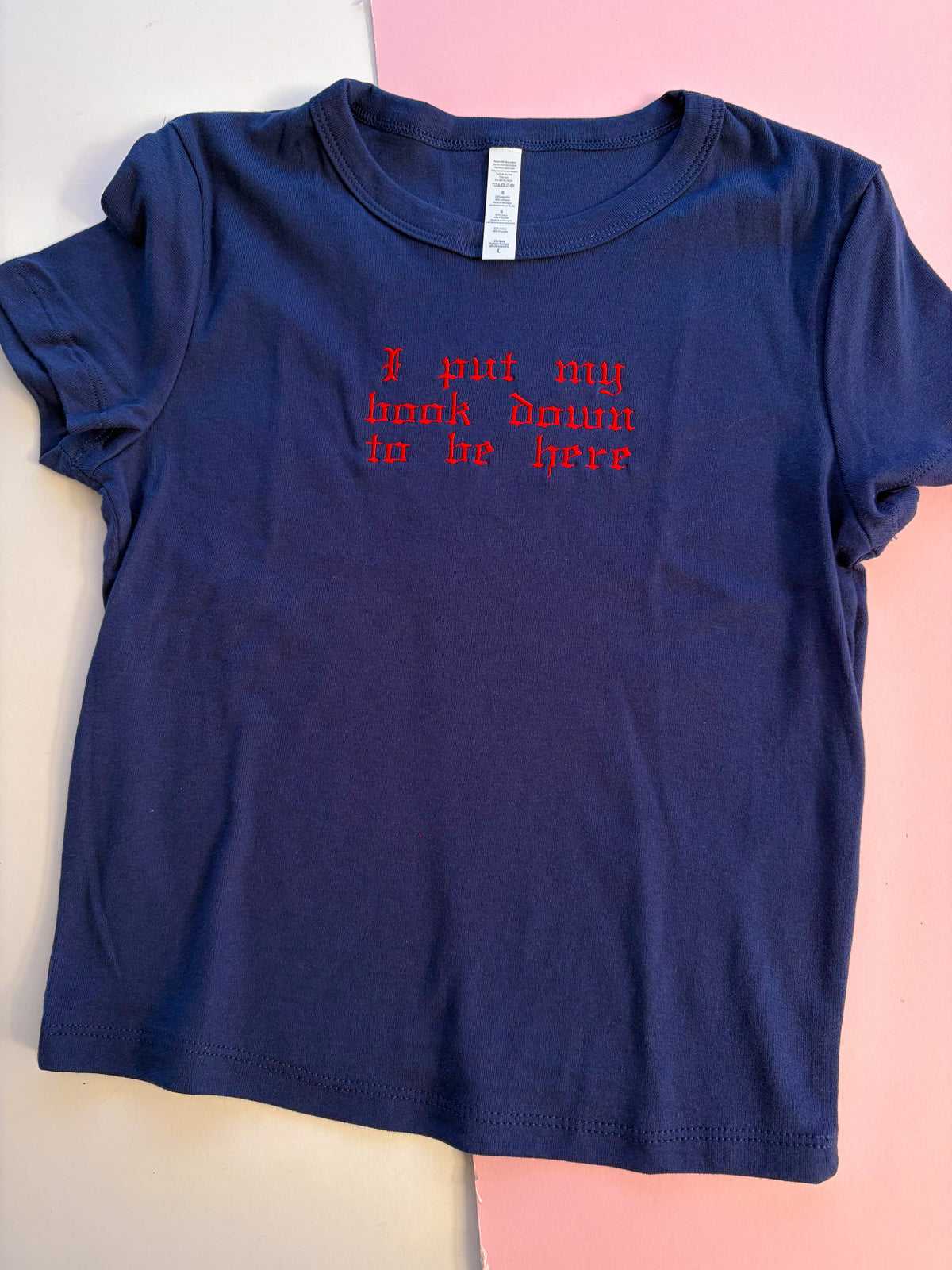 I put my book down to be here baby tee